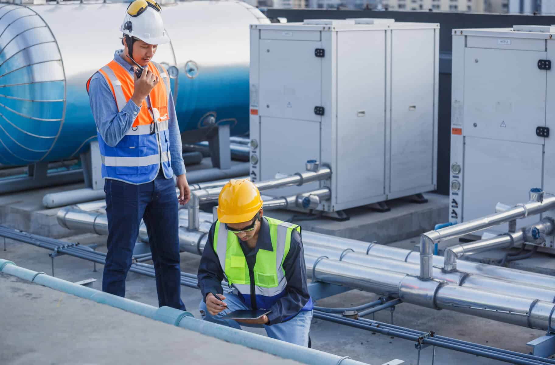 HVAC technician and engineer inspecting industrial heating, ventilation, air conditioning systems on rooftop.